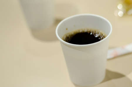 a paper cup of black coffee on wooden tableの写真素材