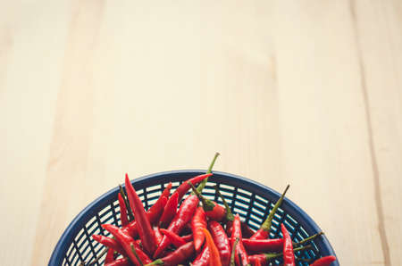 Vintage of half of close up red and green chili in blue plastic basket on wooden backgroundの写真素材