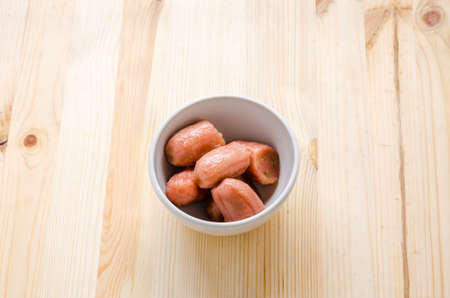 Banana with syrup in white bowl on center of wooden background, Thai dessert.の写真素材