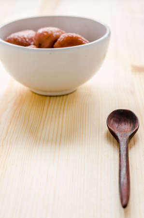 Wooden spoon and red banana with syrup in white bowl on wooden background, Thai dessert.の写真素材