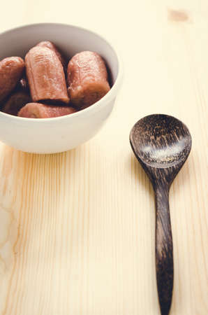 Vintage of banana with syrup in white bowl on wooden background, Thai dessert.の写真素材