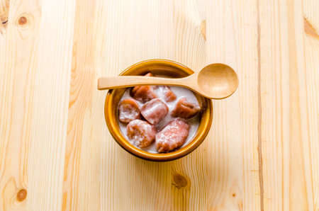 wooden spoon and banana with syrup and coconut milk in brown bowl on wooden background, Thai dessert.の写真素材