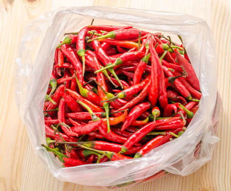 Close up red and green chili in plastic bag on wooden background
