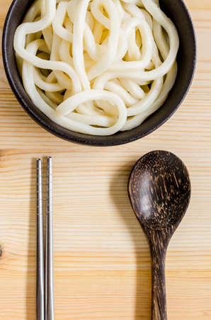 White udon noodle in black bowl on wooden backgroundの写真素材
