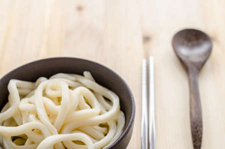 White udon noodle in black bowl on wooden backgroundの写真素材