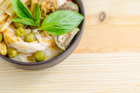 Rice noodles in chicken curry sauce with vegetables on wooden backgroundの写真素材