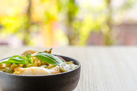 Rice noodles in chicken curry sauce with vegetables on wooden backgroundの写真素材