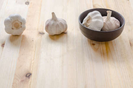Garlic in black bowl on wooden table backgroundの写真素材
