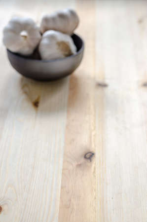 Garlic in black bowl on wooden table backgroundの写真素材