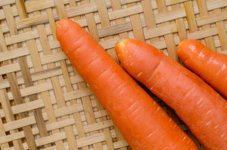 Fresh carrots on the bamboo basket on the wooden table horizontalの写真素材