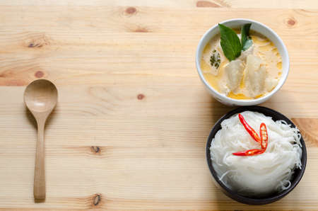 Thai vermicelli eaten with curry, Thai Food, rice vermicelli in black bowl on wooden tableの写真素材