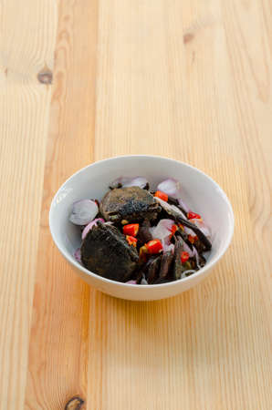 Small black crab sour salad on wooden background, Thai traditional food