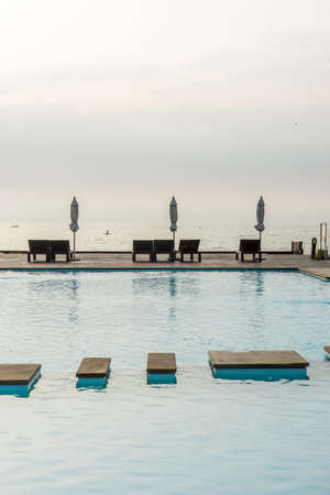 Seafront chair and swimming pool in the morning timeの写真素材