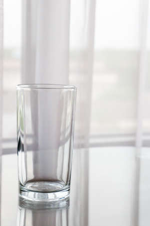 A glass of water containing fresh drinking water. Set on a table and placed in front of the curtain.の写真素材