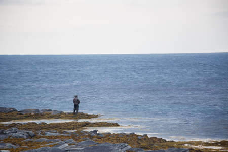 Fisherman with fishing Pole on stone in the north seaの写真素材