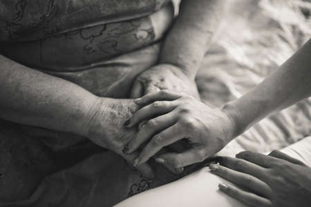 black and white people, age, family, care and support concept - close up of senior woman and young woman holding handsの写真素材