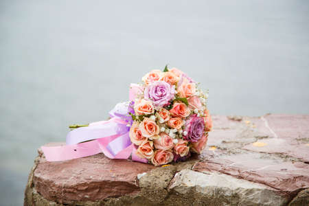 Wide angle shoot bride bouquet of  red and purple rose flowers. over sea background. Wedding, marriage, concept.の写真素材