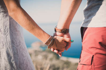 Close up of a happy couple holding hands. Engagement. Love. sea backgroundの写真素材