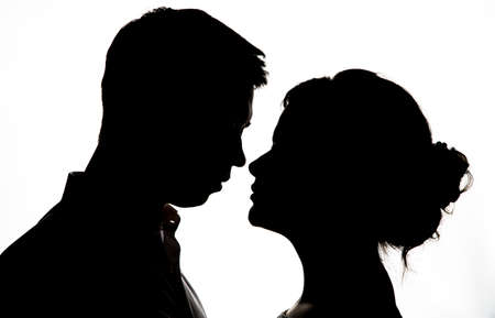Young bride with groom silhouette  with wedding bouquet on a white backgroundの写真素材