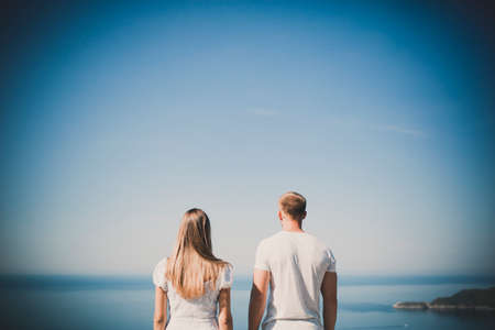 Rear view of happy couple standing against sea. Two lovers in vacationの写真素材