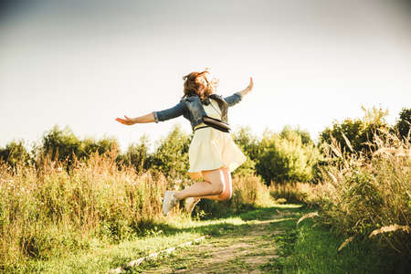 beautyful romantic girl with headphones in a wheat field jumpingの写真素材