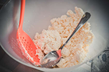 Female hands cook homemade cottage cheese in a bowlの写真素材