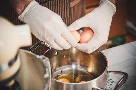 the cooks hands break the egg over the pan
