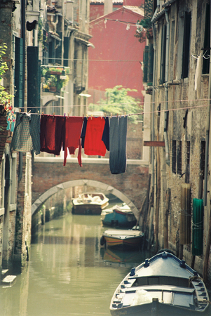 Laundry hang over venice canal between the buildingsの写真素材