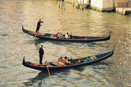 Venzian gondoliers sailing some tourists on their gondola in the tunnels of Veniceのeditorial素材