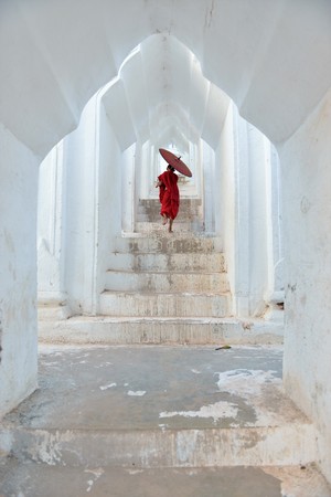 buddhist kids with red robes and umbrellas runningの写真素材