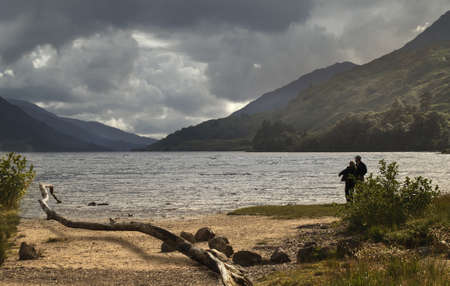 A darkening sky signals the approach of stormy weather by the shore of Loch Shiel in Scotland.の写真素材