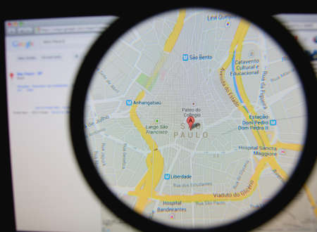 LISBON - JANUARY 29, 2014: Photo of Google Maps pinpointing Sao Paulo on a monitor screen through a magnifying glass.のeditorial素材