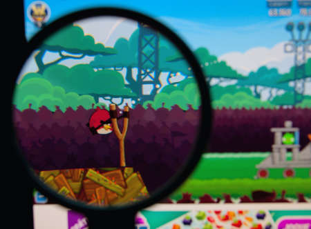 LISBON - JANUARY 29, 2014: Photo of Angry Birds game on a monitor screen through a magnifying glass.のeditorial素材