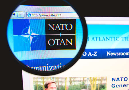 LISBON, PORTUGAL - FEBRUARY 6, 2014: Photo of NATO homepage on a monitor screen through a magnifying...