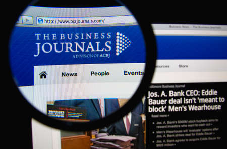 LISBON, PORTUGAL - FEBRUARY 19, 2014: Photo of The Business Journals homepage on a monitor screen through a magnifying glass.のeditorial素材