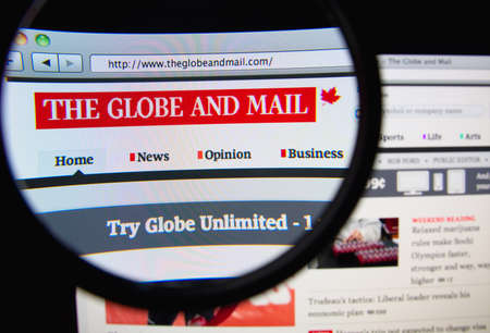 LISBON, PORTUGAL - FEBRUARY 21, 2014: Photo of The Globe and Mail homepage on a monitor screen through a magnifying glass.のeditorial素材