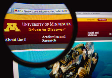 LISBON, PORTUGAL - FEBRUARY 22, 2014: Photo of the University of Minnesota homepage on a monitor screen through a magnifying glass.のeditorial素材
