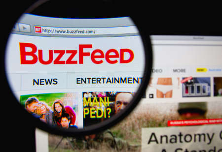 LISBON, PORTUGAL - MARCH 7, 2014: Photo of Buzzfeed homepage on a monitor screen through a magnifying glass.のeditorial素材