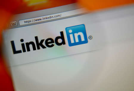 LISBON, PORTUGAL - AUGUST 3, 2014: Photo of LinkedIn homepage on a monitor screen through a magnifying glass.のeditorial素材