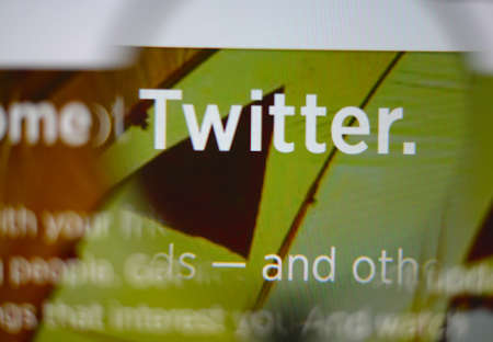 LISBON, PORTUGAL - AUGUST 3, 2014: Photo of Twitter homepage on a monitor screen through a magnifying glass.のeditorial素材