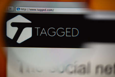 LISBON, PORTUGAL - AUGUST 27, 2014: Photo of Tagged homepage on a monitor screen through a magnifying glass.のeditorial素材