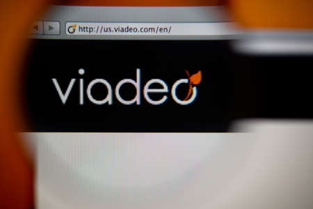 LISBON, PORTUGAL - AUGUST 27, 2014: Photo of Viadeo homepage on a monitor screen through a magnifying glass.のeditorial素材