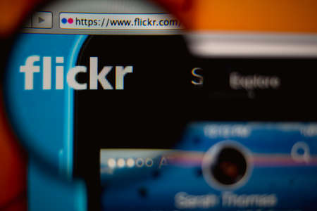 LISBON, PORTUGAL - AUGUST 27, 2014: Photo of Flickr homepage on a monitor screen through a magnifying glass.のeditorial素材