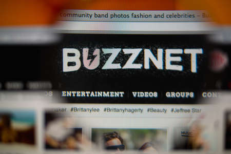 LISBON, PORTUGAL - AUGUST 27, 2014: Photo of BuzzNet homepage on a monitor screen through a magnifying glass.のeditorial素材