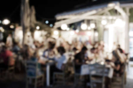 Abstract blurred restaurant background. Blurry cafe or coffee shop with dining tables, chairs and other decorations. Blur backdrop for design element. Food and beverage concept. blurred people. Vintage filterの写真素材