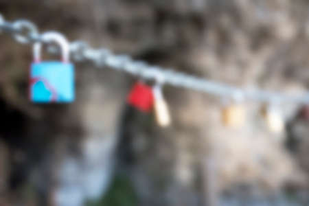 Blurred Many love padlocks locked on chain on a blurred background. Tourists place. Love sign and romance concept.の写真素材