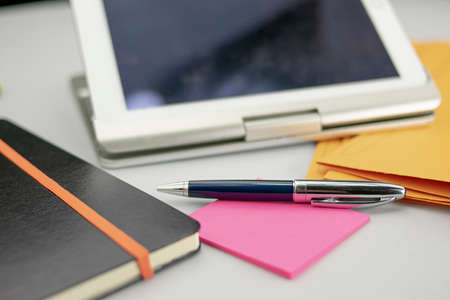 Office supplies consisting of tablet with keyboard, fluorescent marker, red and blue markers, modern pen, sticky notepad and note bookの写真素材