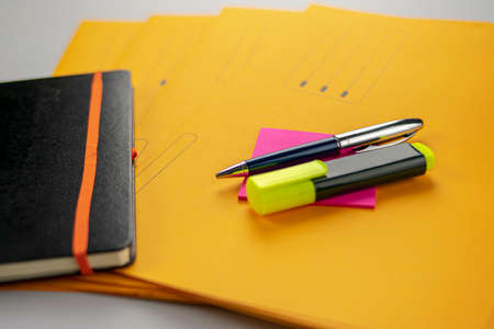 Pen and fluorescent marker on memo note, yellow subfolders and notebookの写真素材