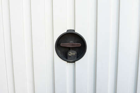 lock of a white automatic garage door with manual opening swivel crankの写真素材