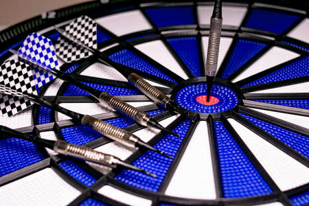 Traditional game of darts composed of target and darts in white and blue colors, with central point in red, and plastic material to avoid dangers and injuries in childrenの写真素材